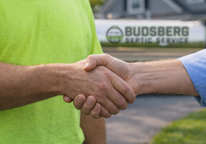 Handshake between customer and septic service professional with Budsberg truck in background